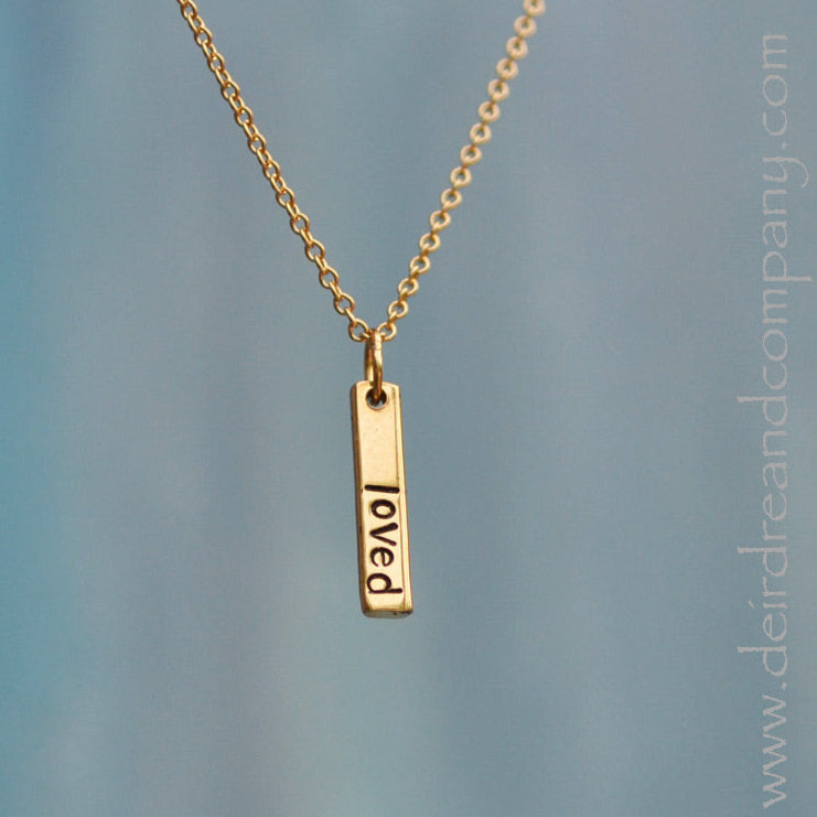 dainty gold bar necklace with the word loved